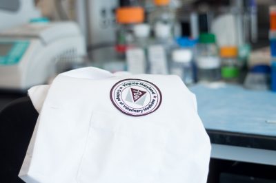 College emblem on folded white coat with laboratory equipment in the background
