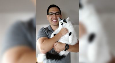 Man holding a large white and black cat.